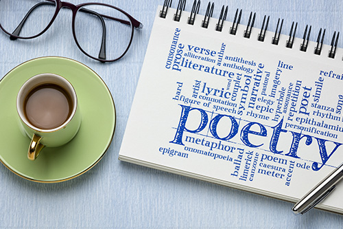 Green coffee cup, glasses and a notebook with "Poetry" written on it