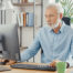 Senior man sitting at a desk and using a desktop computer