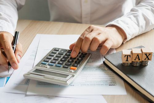 Person doing their taxes using a calculator