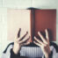 Person with their head behing a hardcover book
