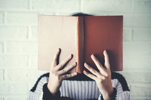 Person with their head behing a hardcover book