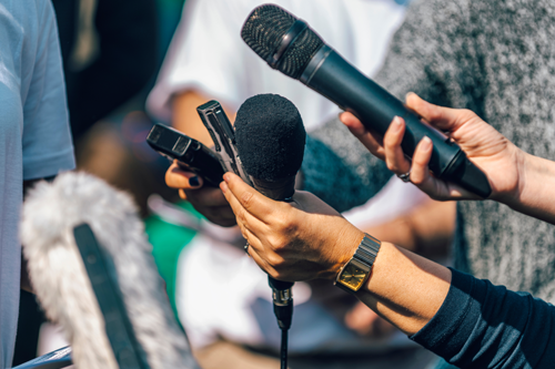 Journalists holding microphones at an interview