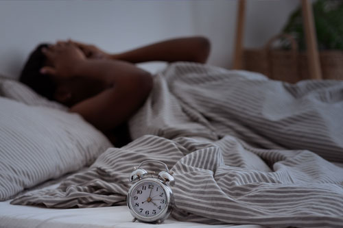 Woman trying to sleep with an alarm clock nect to her bed