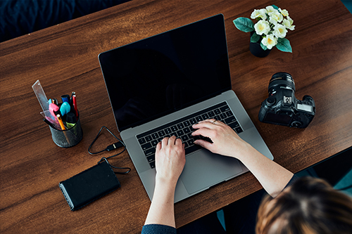 Female photographer working on photos on laptop and camera.